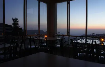 a room with tables and chairs with a view of the ocean at Dana Village lodge and Camp-Wadi Dana Eco camp in Dana