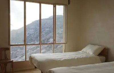 two beds in a room with a large window at Dana Village lodge and Camp-Wadi Dana Eco camp in Dana