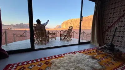 a person sitting in a chair looking out at the desert at Wadi Rum Camp and Tours in Wadi Rum
