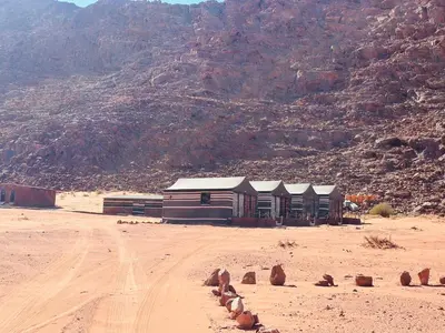 a building in the middle of a desert with a mountain at Wadi Rum Camp and Tours in Wadi Rum