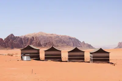 a building in the desert with a mountain in the background at Wadi Rum Camp and Tours in Wadi Rum