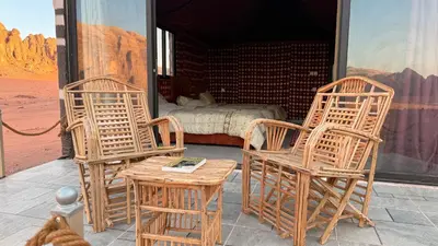 two chairs and a table on a porch with a bed at Wadi Rum Camp and Tours in Wadi Rum