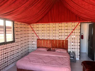 a bedroom with a bed with a red curtain at Wadi Rum Camp and Tours in Wadi Rum