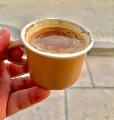 a person is holding a cup of coffee at ريمون هاوس in Kafr Khall