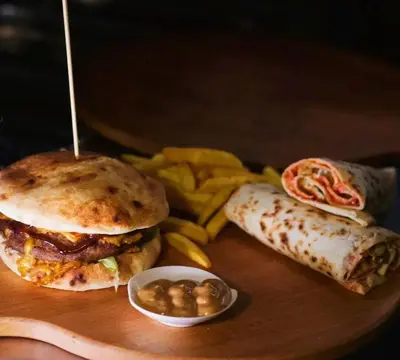 a plate of food with a sandwich and chips and a burrito at ريمون هاوس in Kafr Khall