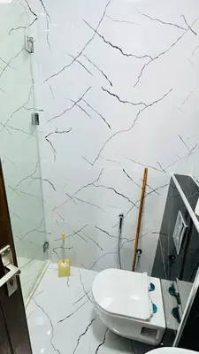 a bathroom with a white toilet and a marble wall at شقق فاخره للايجار in Amman