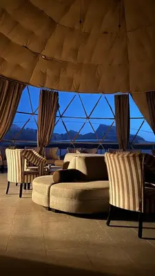 a bedroom with a bed and two chairs and a large window at Kadi Wadi Rum in Al Jafr