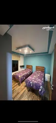 two beds in a room with purple sheets at Apartment in Al Jafr