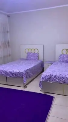 a bedroom with two beds with purple sheets and a purple rug at مليح هوستل