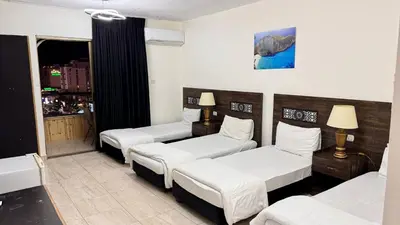 a hotel room with three beds and a window at Eden Hotel in Aqaba