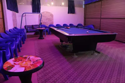 a billiard room with a pool table and blue chairs at استراحة ومنتجع قرية الزرب in Ajloun