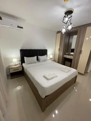 a bedroom with a large bed with white sheets at 2bedroom aprt at 7th circle f-r4 in Amman