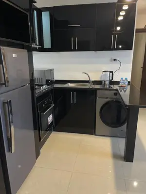 a kitchen with black cabinets and a washer and dryer at 2bedroom aprt at 7th circle f-r4 in Amman