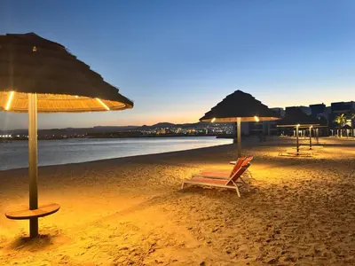 a beach with two chairs and umbrellas on it at Ayla Aqaba Azure 2 bedroom in Aqaba