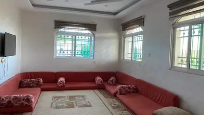 a living room with a red couch and two windows at شاليه جبال سوف in Jerash