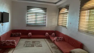 a living room with a red couch and windows at شاليه جبال سوف in Jerash