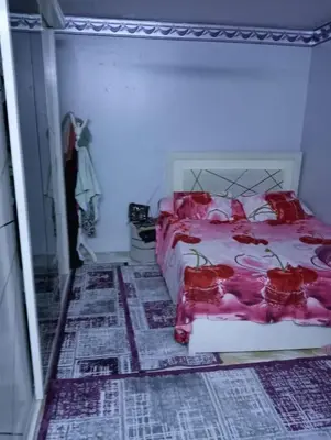 a bedroom with a bed with red flowers on it at ام جوزه هاوس in Umm Jawzah