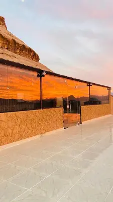 a building with a roof with a sunset in the background at SAHARA ECHO CAMP& Tour in Wadi Rum