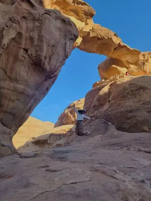 a person standing under an arch in the desert at SAHARA ECHO CAMP& Tour in Wadi Rum