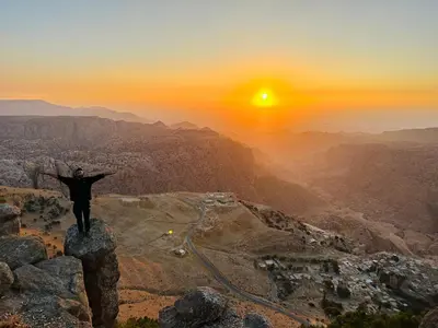 a man standing on top of a mountain at sunset at بيت جدي in Dana