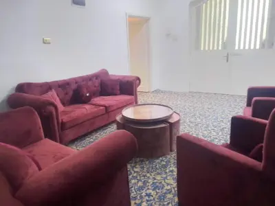 a living room with two red couches and a table at الخير لشقق المفروشه in Al Jafr