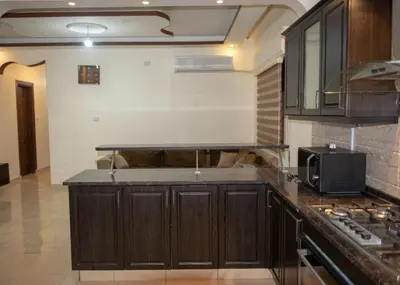 a kitchen with wooden cabinets and a microwave at شقة مفروشة في طبربور 3 غرف نوم in Amman