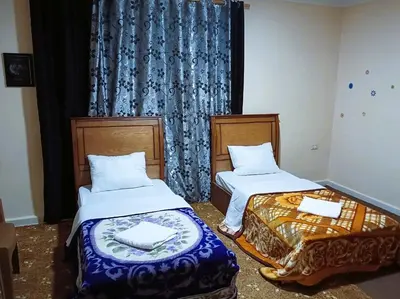 a room with two beds and a window with curtains at Petra Triclinium Home in Wadi Musa