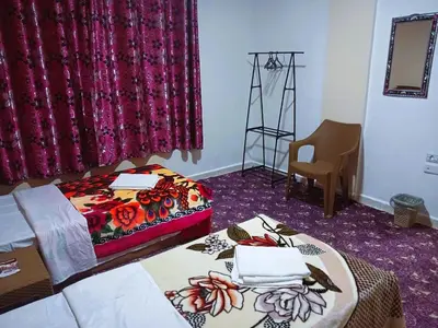 a hotel room with two beds and a chair at Petra Triclinium Home in Wadi Musa
