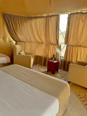 a bedroom with two beds and chairs and a window at Rum marco luxury camp in Wadi Rum