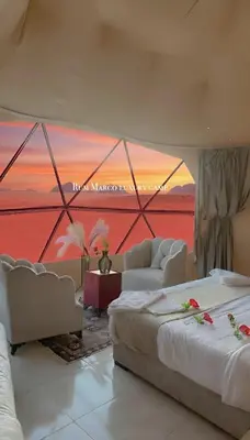 a room with two beds and a sunset in a tent at Rum marco luxury camp in Wadi Rum