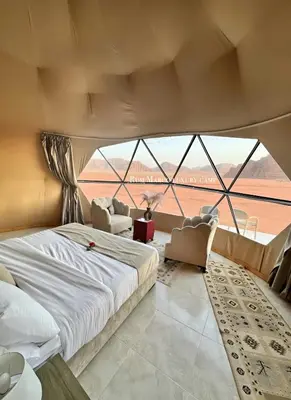 a bedroom with a large bed and a large window at Rum marco luxury camp in Wadi Rum