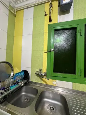 a kitchen sink with a green window and a mirror at سونا موتل in Sūf