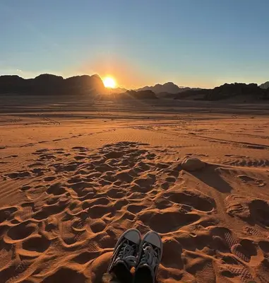 a pair of shoes in the desert with the sunset at Wadi Rum Sand Camp in Al Jafr