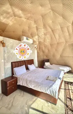 a bedroom with a bed and a wall with a flower on it at Wadi Rum Sand Camp in Al Jafr