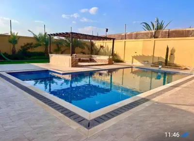 a swimming pool with blue water in a yard at Janna2Villa in Shūnat Nimrīn