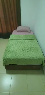 a bed with a green comforter in a room at swahmaya apartments for rent in Sowayma