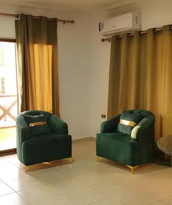 two green chairs in a living room with curtains at swahmaya apartments for rent in Sowayma