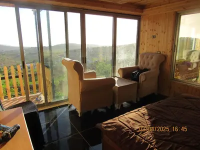 a room with two chairs and a bed and windows at اكواخ الملول عجلون 1 in ‘Ibbīn