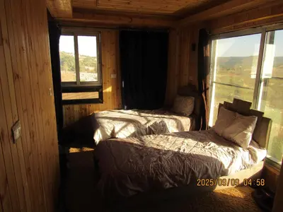 two beds in a room with a window at اكواخ الملول عجلون 1 in ‘Ibbīn