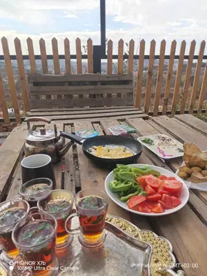 a table with plates of food and drinks and vegetables at اكواخ الملول عجلون 1 in ‘Ibbīn