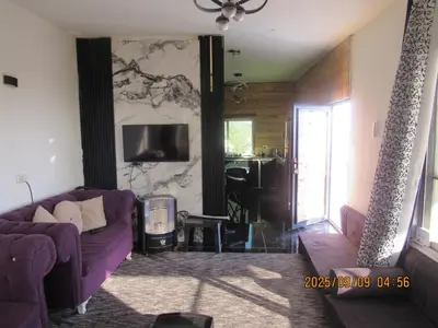 a living room with a purple couch and a tv at اكواخ الملول عجلون 1 in ‘Ibbīn