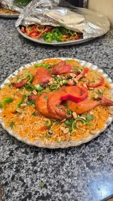 a plate of food with meat and rice on a table at الضليل هاوس in Abū Ghārah