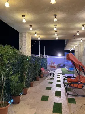 a patio with chairs and potted plants at night at مزرعة وشالية هوى الوادي