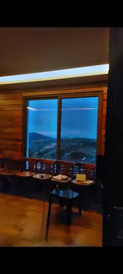 a room with chairs and a large window with a view at Mountain Oak Chalet شالية ملول الجبل in Al Jafr