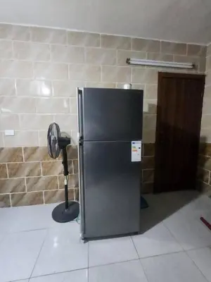 a black refrigerator in a room with a fan at اللجين 6m in Irbid