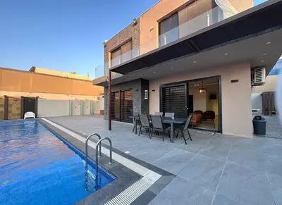a house with a swimming pool in front of a house at SunValley in Al Rama