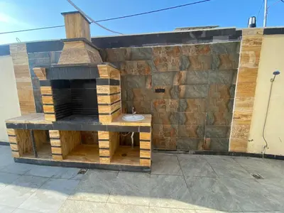 a stone wall with a fireplace on a patio at Nabila Chalet in Sowayma