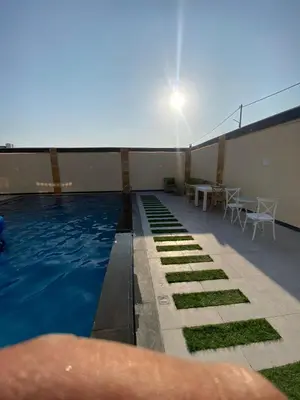 a person is standing next to a swimming pool at Nabila Chalet in Sowayma