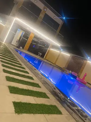 a swimming pool at night with grass in front of a building at Nabila Chalet in Sowayma