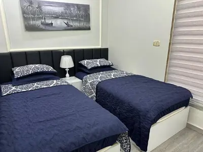 a bedroom with two beds with blue comforters and a picture at استوديو الجاردنز gardens studio 319 in Al Jafr